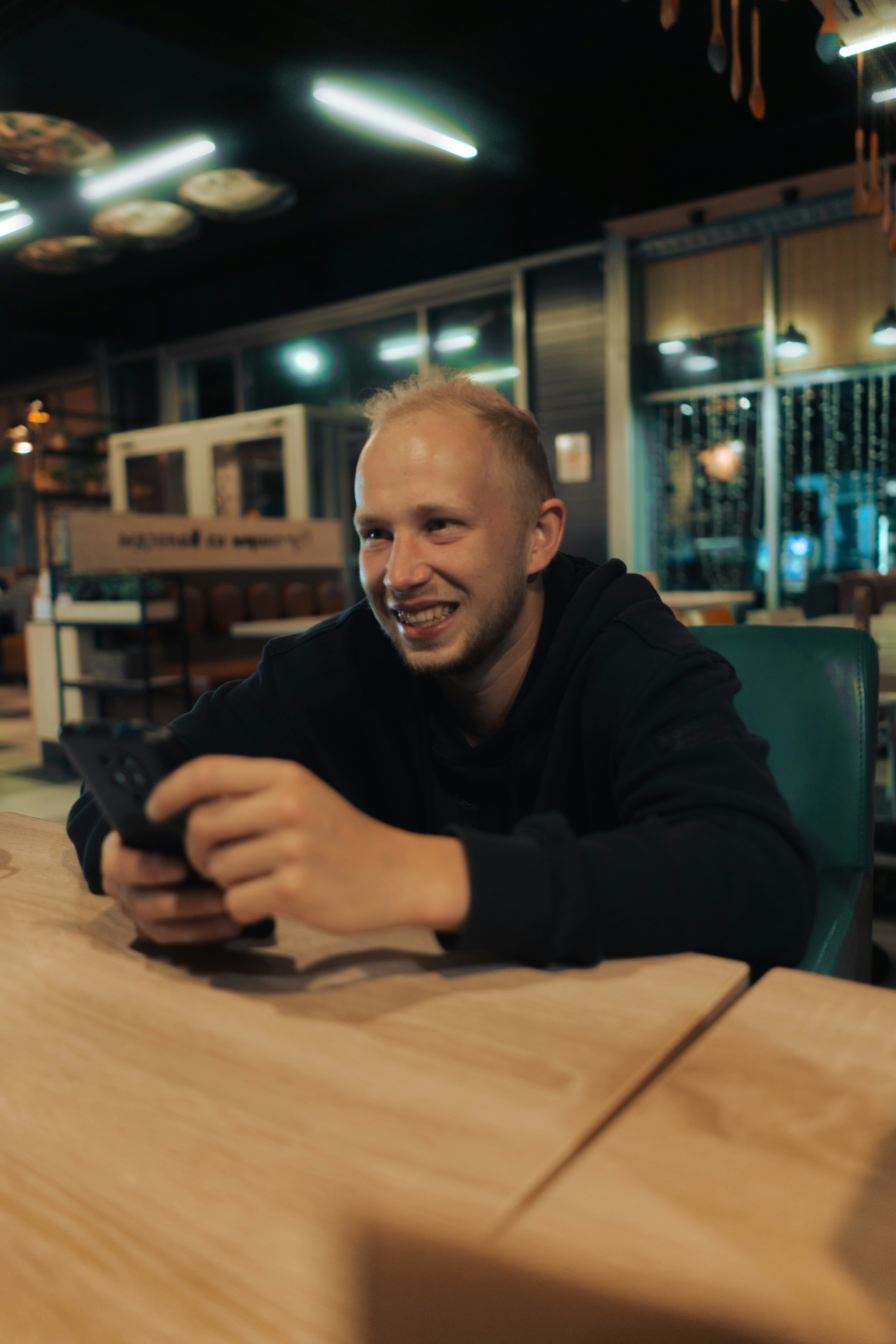 a man sitting at a table looking at a cell phone