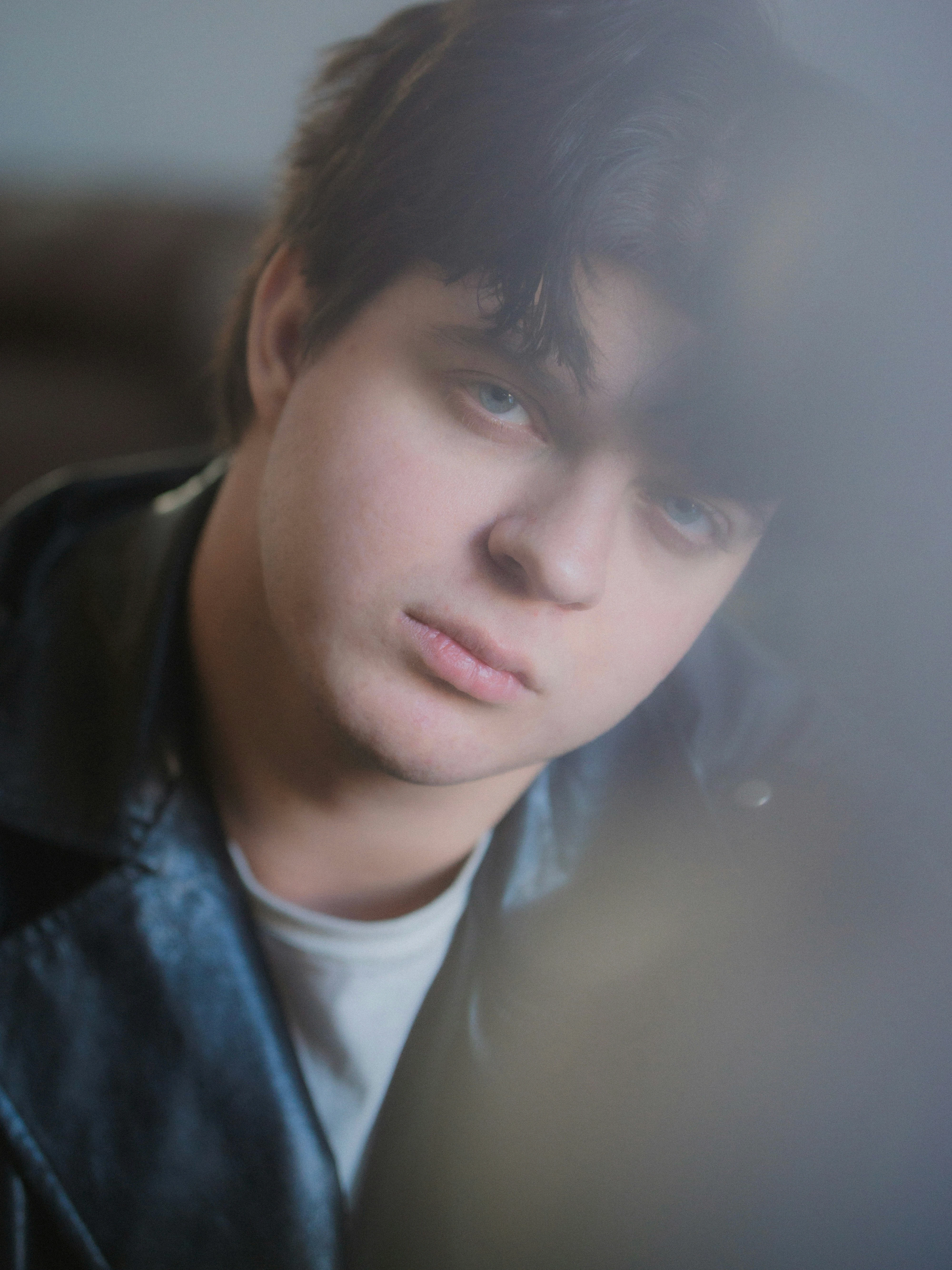 A young man in a leather jacket looking at the camera